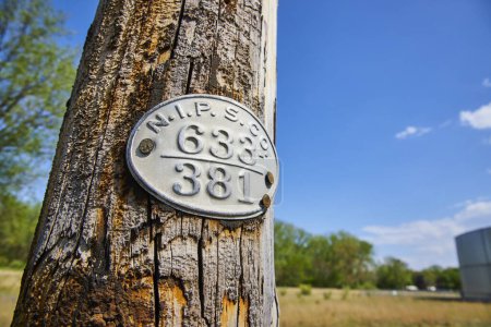 Téléchargez les photos : Bâton en bois vieilli avec plaque historique dans la campagne de Varsovie, Indiana, sous un ciel bleu clair. - en image libre de droit