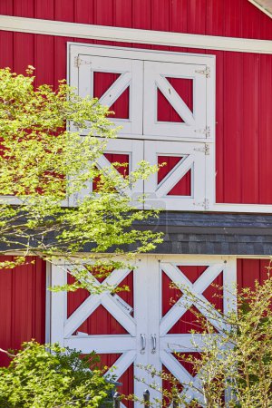 Granero rojo vibrante con puertas blancas en un exuberante entorno de primavera, Fort Wayne, Indiana. Perfecto para temas rurales y agrícolas.