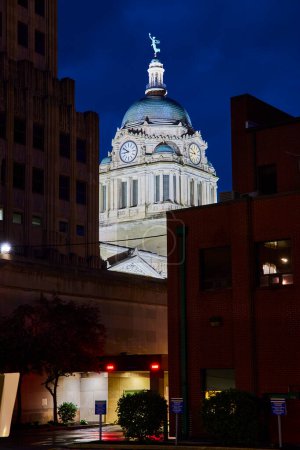 Téléchargez les photos : Dôme lumineux du palais de justice du comté d'Allen la nuit, flanqué de bâtiments modernes au centre-ville de Fort Wayne. - en image libre de droit