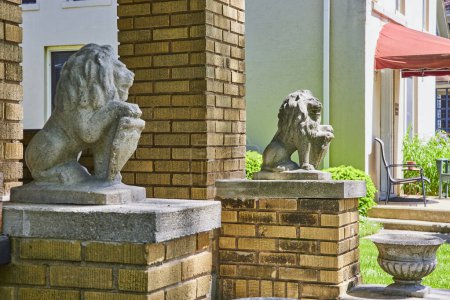 Elegantes leones de piedra custodian una casa histórica en Fort Wayne, simbolizando la tradición y la seguridad bajo un cielo azul claro.
