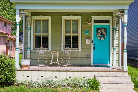Téléchargez les photos : Porche confortable avec porte turquoise et chaises blanches, baignée de soleil dans un quartier paisible de Fort Wayne. - en image libre de droit
