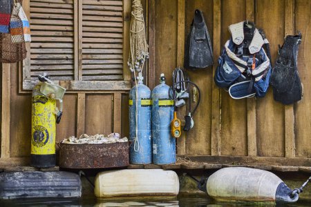 Téléchargez les photos : Équipement de plongée endommagé dans une cabane rustique, prêt pour les aventures sous-marines sur la côte. - en image libre de droit
