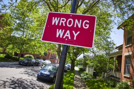 Foto de Vivid WRONG WAY signo en una calle suburbana soleada en Fort Wayne, haciendo hincapié en la seguridad y la dirección. - Imagen libre de derechos