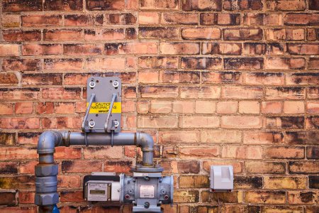 Industrial gas meters on a weathered brick wall in Fort Wayne, highlighting urban utility management.
