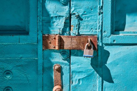 Vibrant turquoise door with rustic metal lock in Fort Wayne: a symbol of aged security and charm.