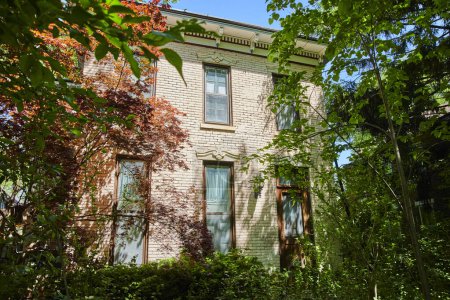 Traditional brick home nestled in lush, green Fort Wayne suburb, radiating tranquility and privacy.