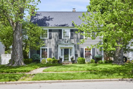 Téléchargez les photos : Élégante maison de banlieue à Fort Wayne, baignée de soleil, présentant une architecture intemporelle et une verdure luxuriante. - en image libre de droit
