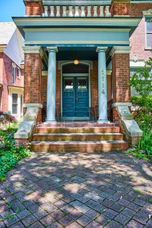 Photo for Traditional brick house with elegant porch in Fort Wayne, bathed in sunlight, evokes warmth and hospitality. - Royalty Free Image