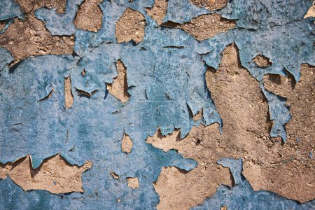 Aging blue paint peels to reveal textured beige layers in a stark portrayal of decay and transformation.