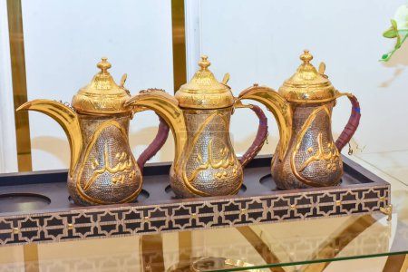 Téléchargez les photos : Gros plan de cafetière culturelle arabe (dalla) ensemble de trois luxe or métallique caféine arabique thé traditionnel qahwa pot ustensile d'hospitalité musulmans - en image libre de droit
