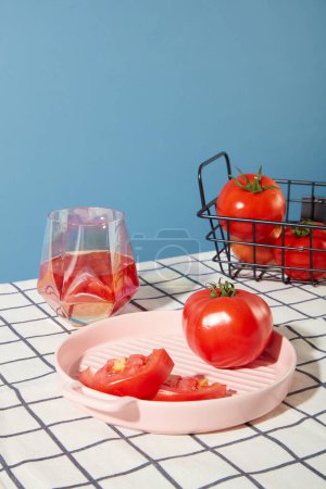 Photo for Fresh tomatoes are displayed on ceramic trays, juicy red tomatoes are stored in an iron mesh basket and a cup of tomato juice is on the table. Take care for health with fresh vegetables. - Royalty Free Image