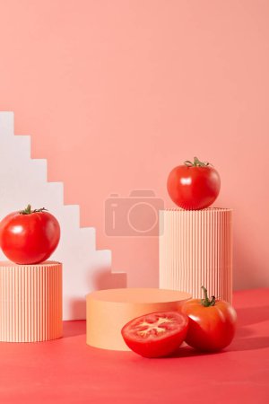 Téléchargez les photos : Vue de face du fond rose créatif avec des tomates et des plates-formes de différentes tailles. Espace d'affichage idéal pour les cosmétiques naturels ou les produits végétaliens. - en image libre de droit