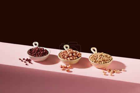 Photo for Three bowls containing red beans, peanuts and soybeans are arranged in line. Some nuts are higher in certain nutrients than others - Royalty Free Image