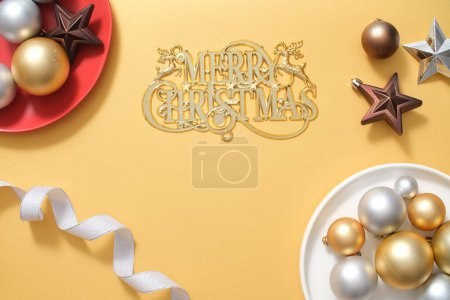 Foto de Composición navideña con fondo dorado con lindo accesorio para decoraciones. Vista superior de adornos de colores, estrella y cinta que se muestra en el fondo amarillo. Feliz Navidad deseos - Imagen libre de derechos