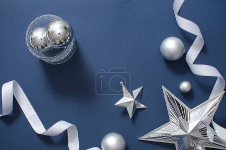 Téléchargez les photos : Cadre décoratif de Noël avec accessoires décoratifs monochromes sur fond bleu foncé. Les étoiles, différentes tailles de boules et de rubans affichés, créent un espace pour le design - en image libre de droit