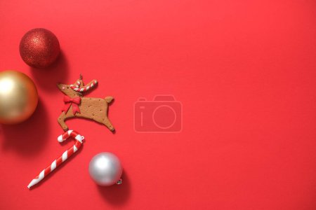 Téléchargez les photos : Vue de dessus de jolies boules, décorées de rennes et de cannes à bonbons sur fond rouge. Noël concept de vacances. Fond d'art minimal avec espace de copie pour la conception. Pose plate - en image libre de droit
