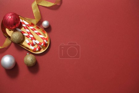 Téléchargez les photos : Composition de Noël avec des boules, des cannes à bonbons et un ruban jaune décoré sur fond rouge. Espace vide pour ajouter du texte ou souhaits. Idées de conception de carte de Noël - en image libre de droit