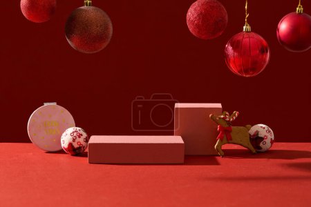 Foto de Foto publicitaria con concepto de decoración navideña. Vista frontal de podios rectangulares vacíos mostrados sobre fondo rojo con adornos rojos brillantes - Imagen libre de derechos