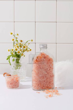 Téléchargez les photos : Beaucoup de sel rose himalayen contenu dans une bouteille transparente et un bol. Concept de salle de bain et style de vie. Le sel rose himalayen peut apporter des bienfaits pour la santé - en image libre de droit