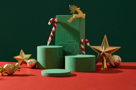 Téléchargez les photos : Concept de décoration de Noël avec accessoire doré et podiums vides affichés sur fond vert. Scène pour la publicité avec espace vide pour les produits de présentation. Vue de face - en image libre de droit