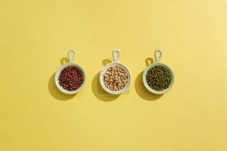 Photo for Three ceramic bowls containing red beans, soybeans and green beans arranged in a line. Beans are a strong, plant-based source of protein, fiber, iron, and vitamins - Royalty Free Image