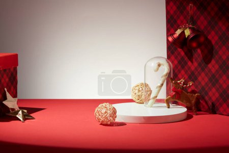 Foto de Concepto para Navidad con fondo liso y objetos rojos para la decoración - caja de regalo con patrones a cuadros, renos pequeños, estrellas y campanas. Vista frontal, espacio vacío para el producto o diseño de la pantalla - Imagen libre de derechos