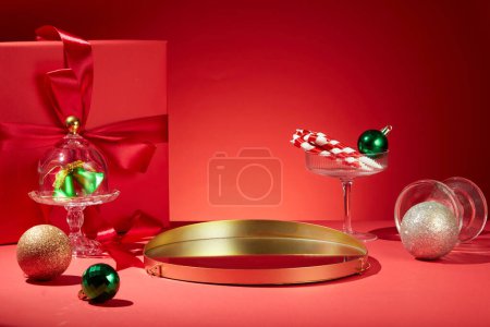 Téléchargez les photos : Fond rouge créatif pour la publicité de produits de Noël. De jolies boîtes-cadeaux, des boules et un plateau doré créent de l'espace pour l'affichage des produits. Vue de face. Noël est la célébration de la naissance de Jésus - en image libre de droit