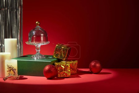 Foto de Ideas para decorar la mesa de Navidad con tonos rojos. Decoraciones coloridas se colocan en la mesa, perlas, cajas de regalo de velas perfumadas están decoradas con estantes de vidrio. Espacio en blanco para texto y diseño - Imagen libre de derechos