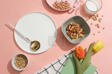 Photo for Various nuts and beans are arranged over pink background. Ceramic dish with blank space to show your product extracted from organic nuts and beans - Royalty Free Image