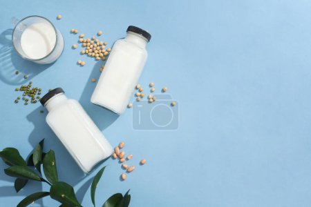 Photo for Two blank label bottles and a glass cup filled with milk displayed with green beans, soybeans and peanuts. Copy space. Concept of organic foods advertising - Royalty Free Image