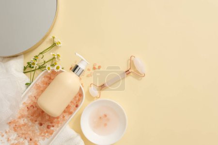 Photo for Lots of pink himalayan salt displayed on ceramic dish with an unlabeled pump bottle placed on. Some daisy flowers decorated. Mockup design and empty space for text adding - Royalty Free Image