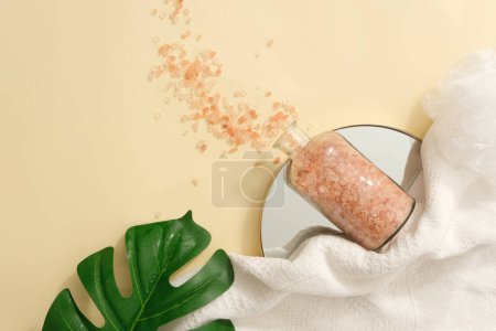 Photo for View from above of a bottle of pink himalayan salt placed on a mirror in round shaped. Green leaf and white towel displayed. Himalayan salt is less artificial and does not usually contain additives - Royalty Free Image