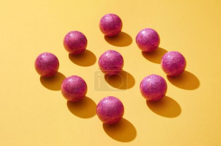 Foto de En el fondo amarillo, las brillantes bolas púrpuras están dispuestas cuidadosamente en forma de rombo. Adorno simbólico para Navidad. Las bolas aportan fuerza y optimismo - Imagen libre de derechos