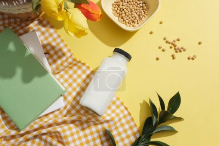 Photo for A white and orange checkered fabric featured books and a milk bottle. Few roses decorated with soybeans. Container packaging of beverages extracted from Soybean (Glycine max) - Royalty Free Image