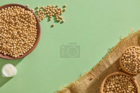 Photo for Soybeans seeds are contained inside some wooden and bamboo containers. A beaker of soybean milk displayed. Blank space in the middle for product presentation - Royalty Free Image