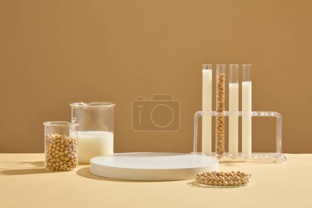Photo for A petri dish, beaker and test tubes on the rack containing soybeans and milk displayed with a podium. Blank space on the podium to display product extracted from Soybean (Glycine max) - Royalty Free Image