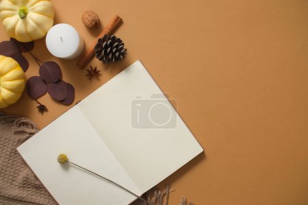 Photo for Photography warm autumn concept Notebook, pumpkins, dried leaves and wool scarf decorated on brown background. Top view, space for design and text - Royalty Free Image