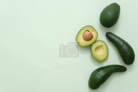 Photo for Minimal blank background with copy space for display cosmetic product. Fresh avocados and avocado slices decorated on pastel green background. Scene for advertising cosmetic of avocado extract - Royalty Free Image