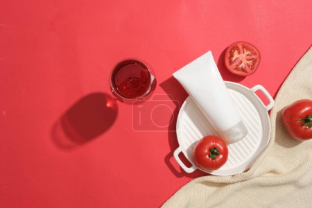 Photo for White tube without label displayed with tomatoes and a wine glass. Mockup design with empty label. Tomato (Solanum lycopersicum) can improve skin health - Royalty Free Image