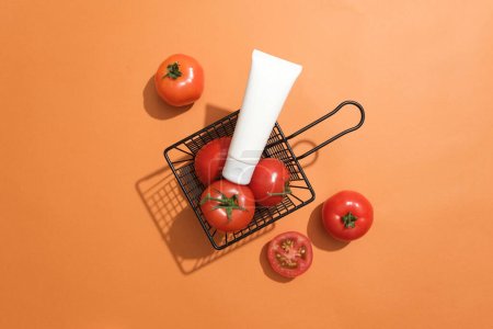 Téléchargez les photos : Un panier contenant des tomates fraîches avec un non étiqueté placé sur le dessus. Fond orange. La teneur en vitamine B du complexe présent dans les tomates aide à combattre les signes du vieillissement de la peau - en image libre de droit