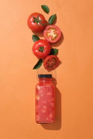 Téléchargez les photos : Bouteille vide de jus de tomate décorée de tomates rouges et de quelques feuilles vertes. Le jus de tomate est riche en nutriments comme la vitamine C, vitamines B et potassium - en image libre de droit