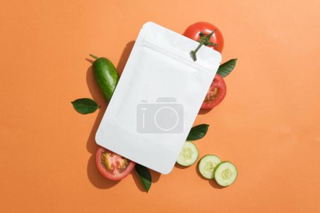 Photo for Facial mask package without label placed on slices of tomato and cucumber. Tomatoes help by closing down the pores and maintaining the pH levels - Royalty Free Image