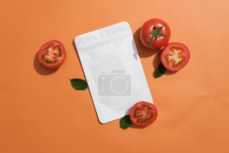 Photo for An unbranded facial mask package decorated with few halves of tomato over orange background. Natural cosmetic concept. Empty label for branding mockup - Royalty Free Image