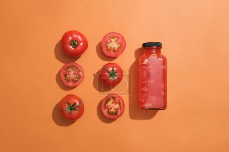 Foto de Tomates y rodajas de tomate dispuestos en dos líneas con una botella de jugo de tomate. Diseño burlón. El contenido de agua de los tomates es de alrededor del 95% - Imagen libre de derechos