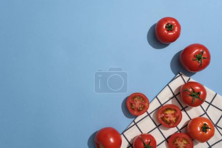 Téléchargez les photos : Vue de dessus de tomates fraîches décorées sur fond bleu avec un tissu. Espace vide pour la promotion des produits extraits de tomates (Solanum lycopersicum) - en image libre de droit