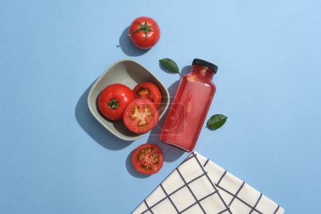 Foto de Las rodajas de tomate están contenidas dentro de un tazón de cerámica decorado con una botella de jugo de tomate. Los tomates (Solanum lycopersicum) son jugosos y dulces, llenos de antioxidantes - Imagen libre de derechos