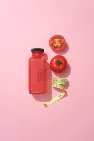 Photo for Pink background featured tomatoes, a tap measures and unlabeled bottle filled with tomato juice. Tomatoes (Solanum lycopersicum) are generally well tolerated - Royalty Free Image