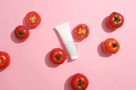 Foto de Varios tomates rojos rodearon un tubo blanco con etiqueta vacía. Etiqueta en blanco de belleza natural para el concepto de maqueta de marca de extracto de tomate (Solanum lycopersicum) - Imagen libre de derechos