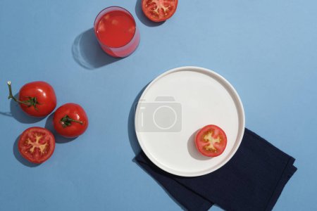 Téléchargez les photos : Verre à jus de tomate décoré de tomates et un plat placé sur un tissu. Les tomates protègent la peau des effets nocifs de l'environnement - en image libre de droit
