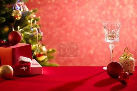 Téléchargez les photos : La surface rouge comportait des boules de Noël, du verre à vin et des boîtes-cadeaux. Espace vide au milieu pour montrer votre produit. Élégante saison des fêtes carte sociale post numérique - en image libre de droit